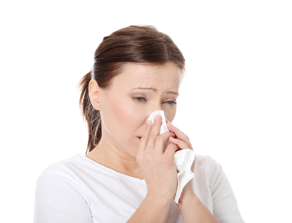 woman sneezing into tissue paper